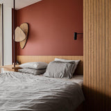 Cane sconce on a terracotta bedroom wall above a bed and slatted wood panels