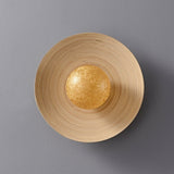 The curved bamboo disc at an angle showing the gold orb set in its hollow
