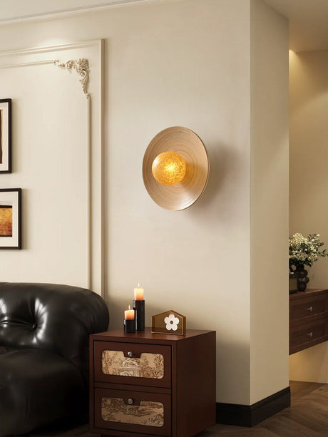 Sconce lit in a living room above a dresser with candles and framed prints
