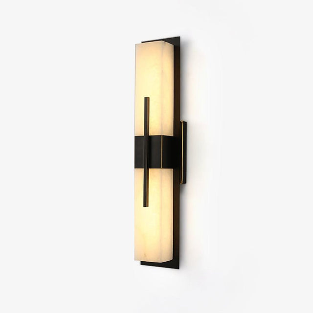 Tall bar wall sconce with a white faux alabaster panel held by a black band, lit warm