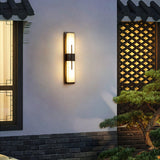 The light lit on a courtyard wall beside a wood lattice screen and a clipped pine