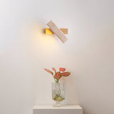 Sconce lit above a nightstand with tulips in a glass vase beside a bed