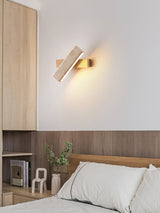 Sconce lit above a bed against a wood panel wall with books on a shelf