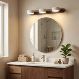 Travertine bar lit above a round mirror on a wood bathroom vanity