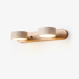 Bathroom vanity sconce with three travertine discs on a light wood bar
