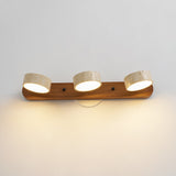 Three travertine discs lit on a dark walnut bar with black hardware