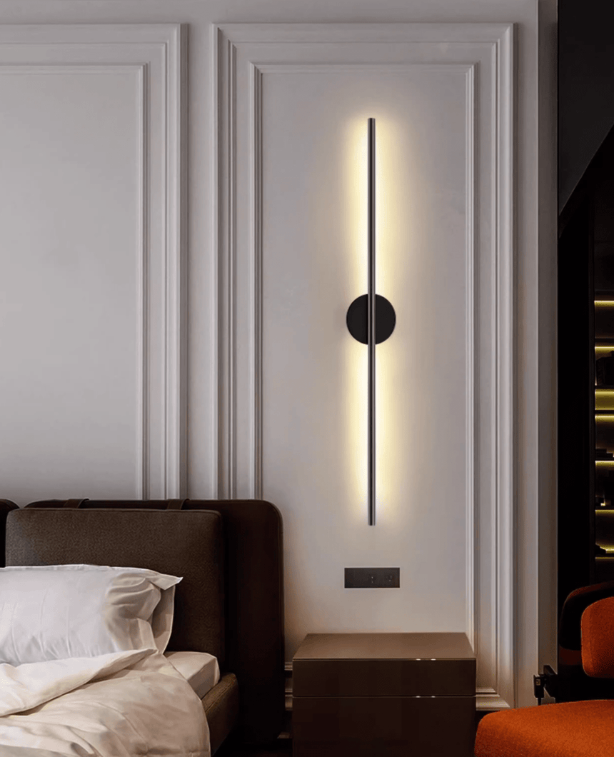 Lit above a bed with a dark headboard, a leather trunk standing alongside