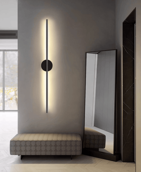 Lit beside a tall leaning mirror above a low upholstered bench and window