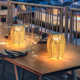 Two lit on a timber table beside glasses on a balcony at dusk