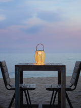 One lit on a high table with two chairs facing the sea at dusk