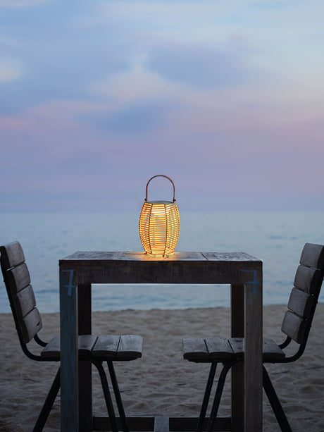 One lit on a high table with two chairs facing the sea at dusk