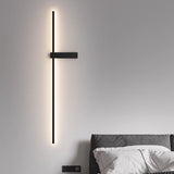 Lit above a bed with white pillows, the rod running down beside the headboard