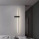 Lit on a bedroom wall beside a bed with pale bedding and a dark partition