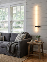 Lit above a gray sofa beside a wood side table with a mug and a book on it