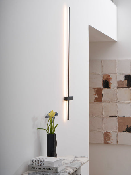 Lit beside a tiled wall above a console holding a vase and a stack of books