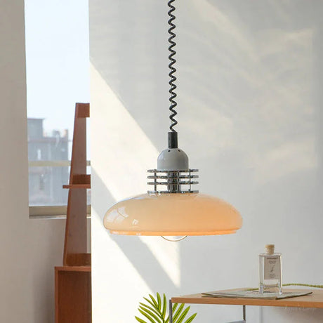 The saucer shade lit in a sunlit room beside a shelf and a window