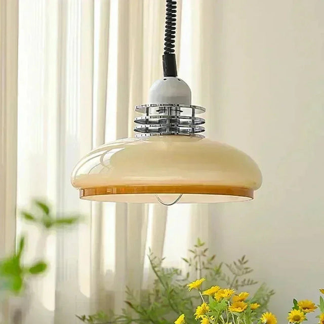 The cream glass saucer shade lit beside a window with yellow flowers