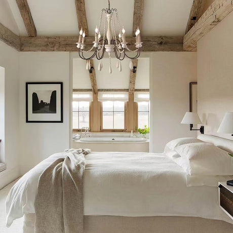 Hung in a bedroom under exposed beams above a made bed with a window behind
