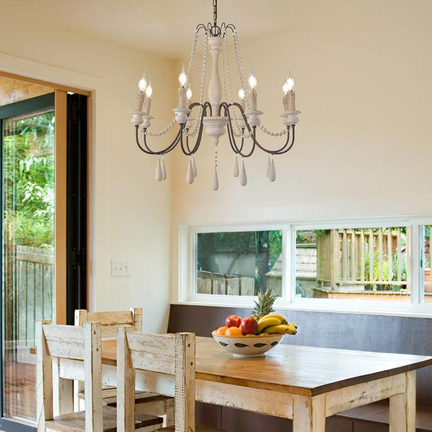 Hung above a pale wood dining table and chairs beside an open garden door
