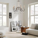 Lit in a pale living room between tall windows above a sofa and a low table