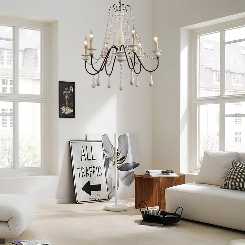 Lit in a pale living room between tall windows above a sofa and a low table