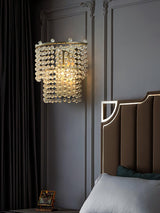 The beaded sconce lit on a dark paneled wall beside a channel tufted headboard
