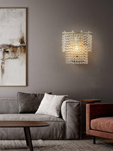 The beaded sconce lit above a gray sofa beside an abstract painting