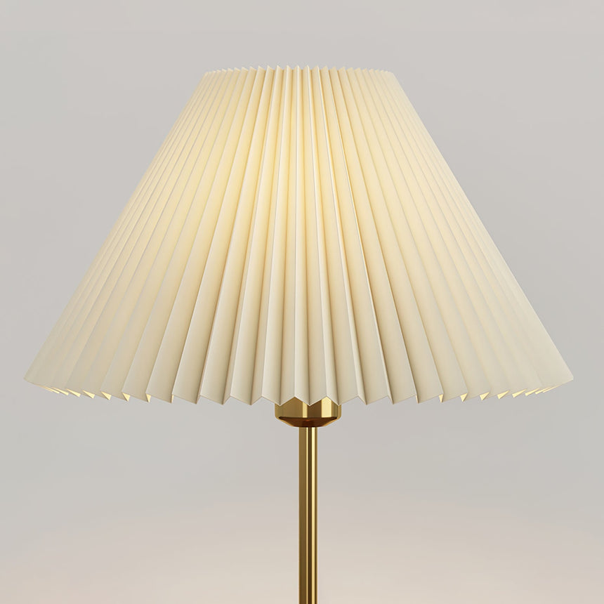 Close view of the folds of the white pleated shade above the brass stem