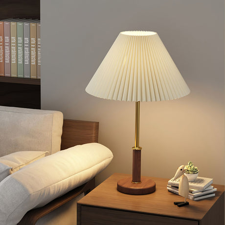Pleated shade lamp lit on a side table beside a pale sofa and a tray