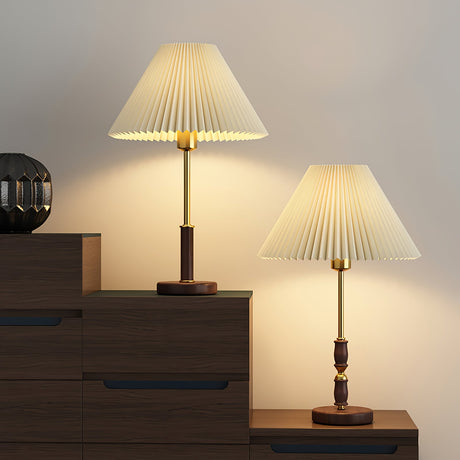 Two pleated shade lamps lit on dark wooden furniture in a pale room