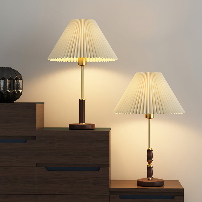 Two pleated shade lamps lit on dark wooden furniture in a pale room