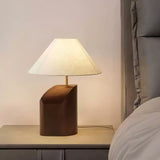 Bedroom table lamp lit on a nightstand beside a bed