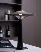 Bedroom table lamp lit in front of a dark shelf with bottles