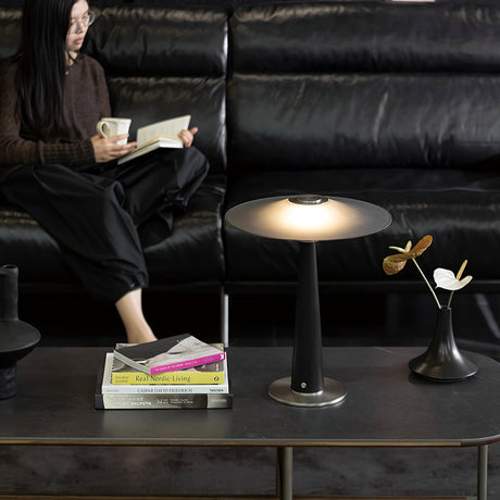 Bedroom table lamp lit on a table in front of a black leather sofa
