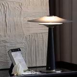 Bedroom table lamp lit beside a textured white plaster wall