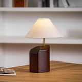 Close view of the lamp lit on a desk, the linen shade in the foreground