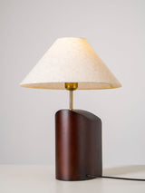 Three quarter view of the curved walnut base and the linen shade