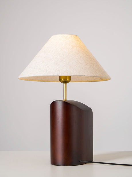 Three quarter view of the curved walnut base and the linen shade