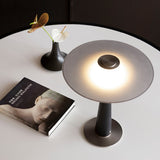 The wide disc of the bedroom table lamp seen lit from above