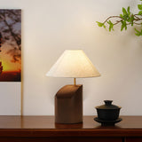 Bedroom table lamp lit beside a framed artwork and a dark bowl