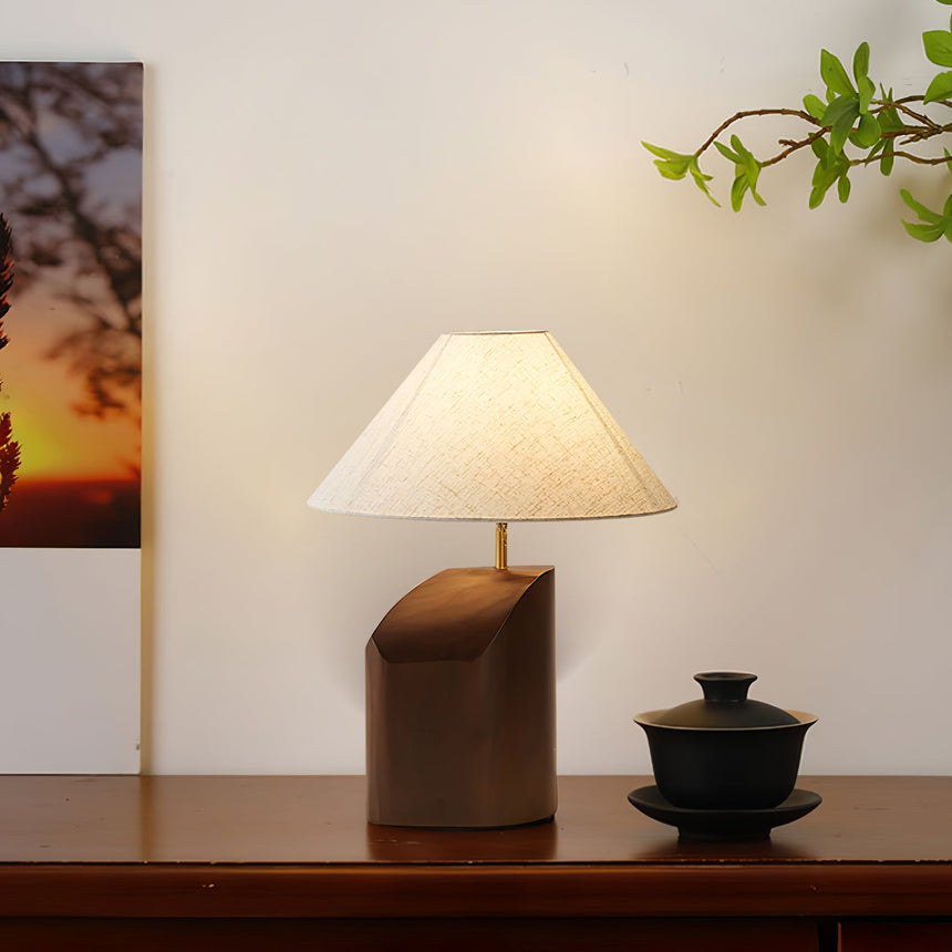 Bedroom table lamp lit beside a framed artwork and a dark bowl