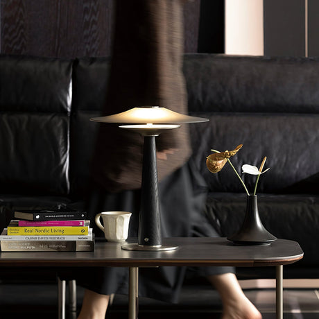 Bedroom table lamp lit on a table in a dark room beside a sofa