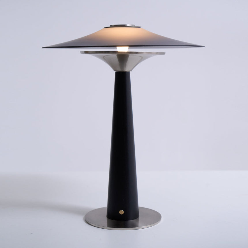 Bedroom table lamp lit and seen from the front on a plain ground