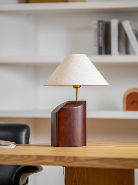 Bedroom table lamp lit on a desk beside an office chair