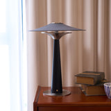 Bedroom table lamp lit on a cherry chest beside old books