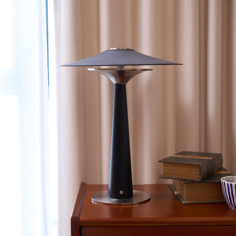 Bedroom table lamp lit on a cherry chest beside old books