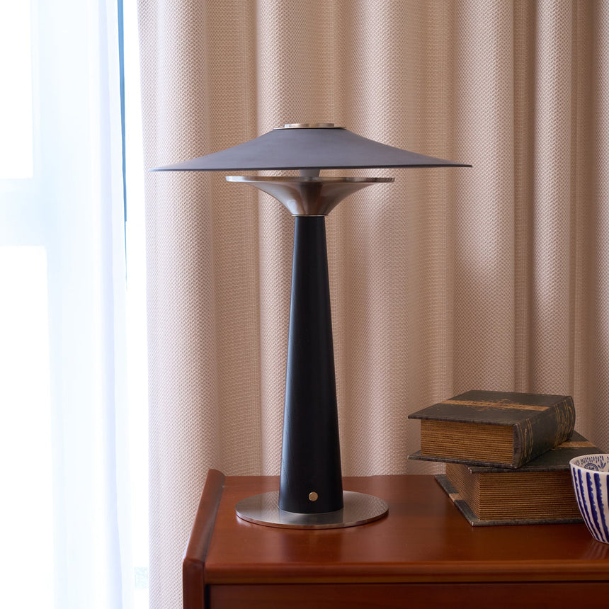Bedroom table lamp lit on a cherry chest beside old books