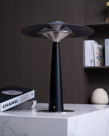 Bedroom table lamp on a marble plinth beside a book and a vase