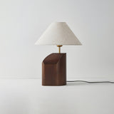 Bedroom table lamp unlit on a plain background, the curved base visible