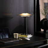Bedroom table lamp lit on a desk beside a laptop and a mug